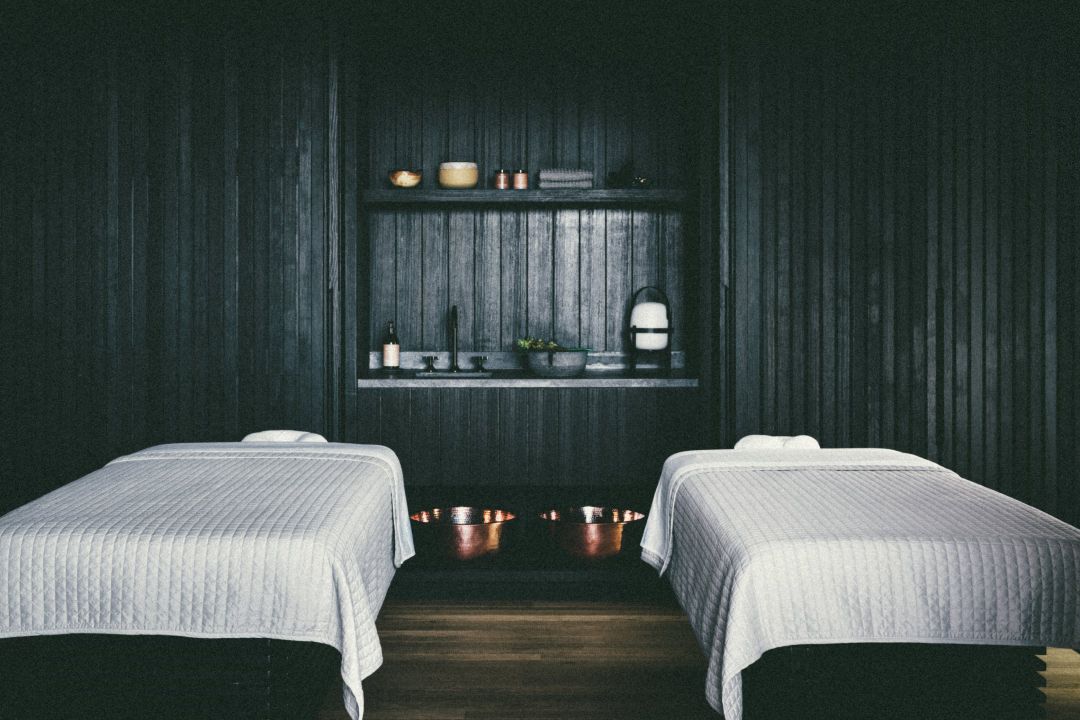 A Hawaiian spa room with two massage tables covered in white sheets.